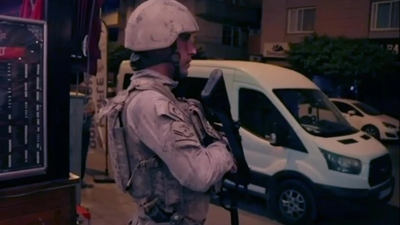 Emniyet ekipleri ve siyah araçlar, operasyon kapsamında bir binanın önünde bekliyor.