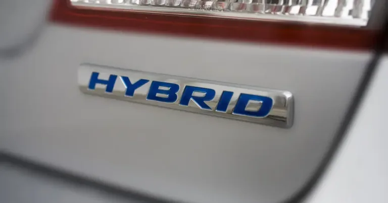 Hibrit otomobillerin önünde duran ve incelemeye alan bir kişi veya model otomobilin detayı.