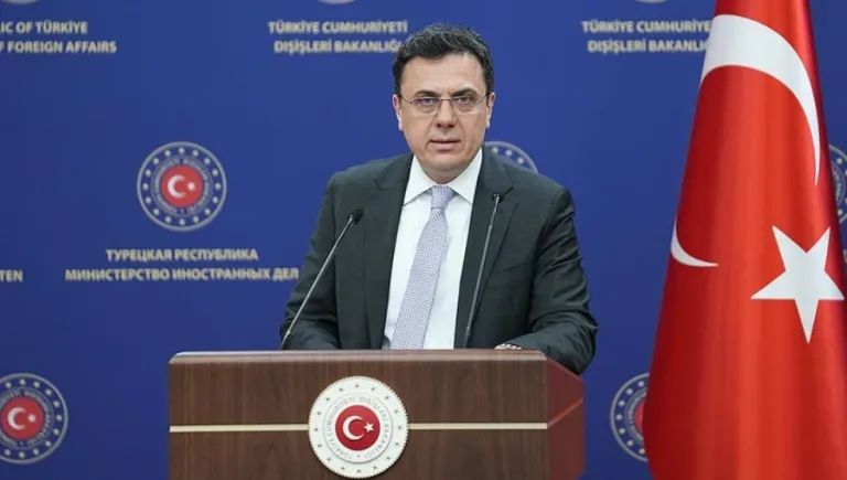 TC Dışişleri Sözcüsü Keçeli konuşma yaparken mikrofon ve arka planda toplantı atmosferi
