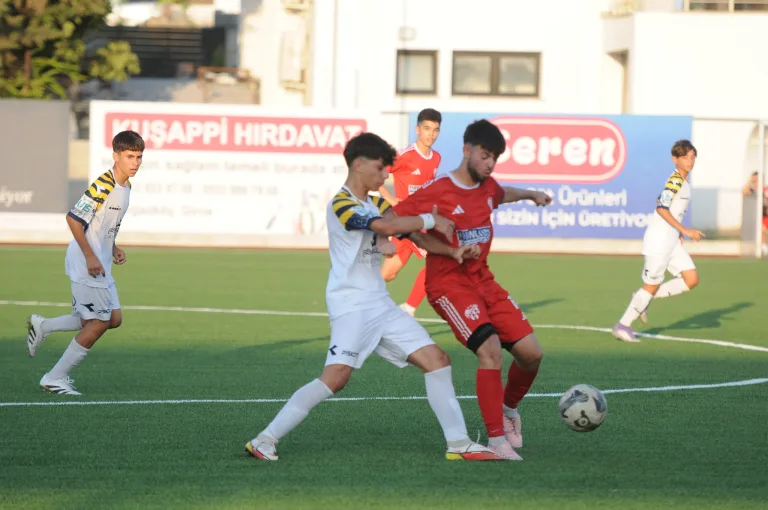 Saydam U15 Ligi maç sahasında genç futbolcular karşılaşma anında, tribünler ve maç görevlileri görünür