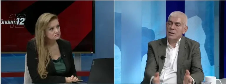 Kamacıoğlu konuşurken mikrofon önünde, iş insanları ve sanayi vurgusunu temsil eden bir etkinlik sahnesi