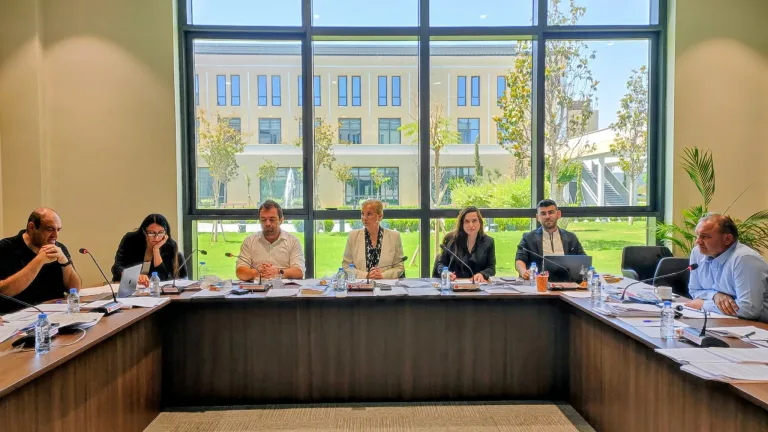 Komitede bir grup milletvekili tartışma halinde, masa ve belgelerle toplantı ortamı