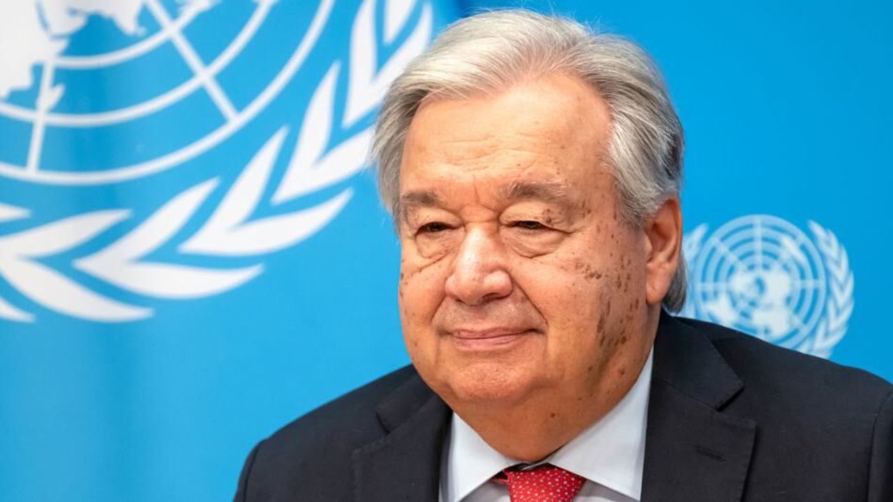 Guterres konuşma yaparken kürsüde, arka planda uluslararası semboller ve mikrofonlar