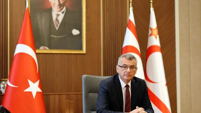 Erhürman konuşurken ciddiyetle dinleyen gençler ve arka planda nötr bir toplantı ortamı
