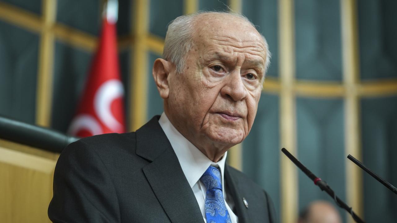 Devlet Bahçeli konuşma yaparken mikrofon önünde ve ciddi bir ifadeyle duruyor
