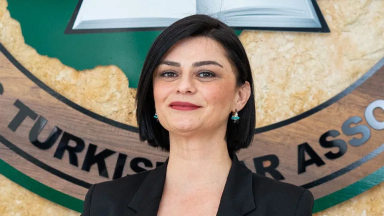 Aslı Murat konuşurken, arka planda boş bir sandalye ve resmi panonun silueti
