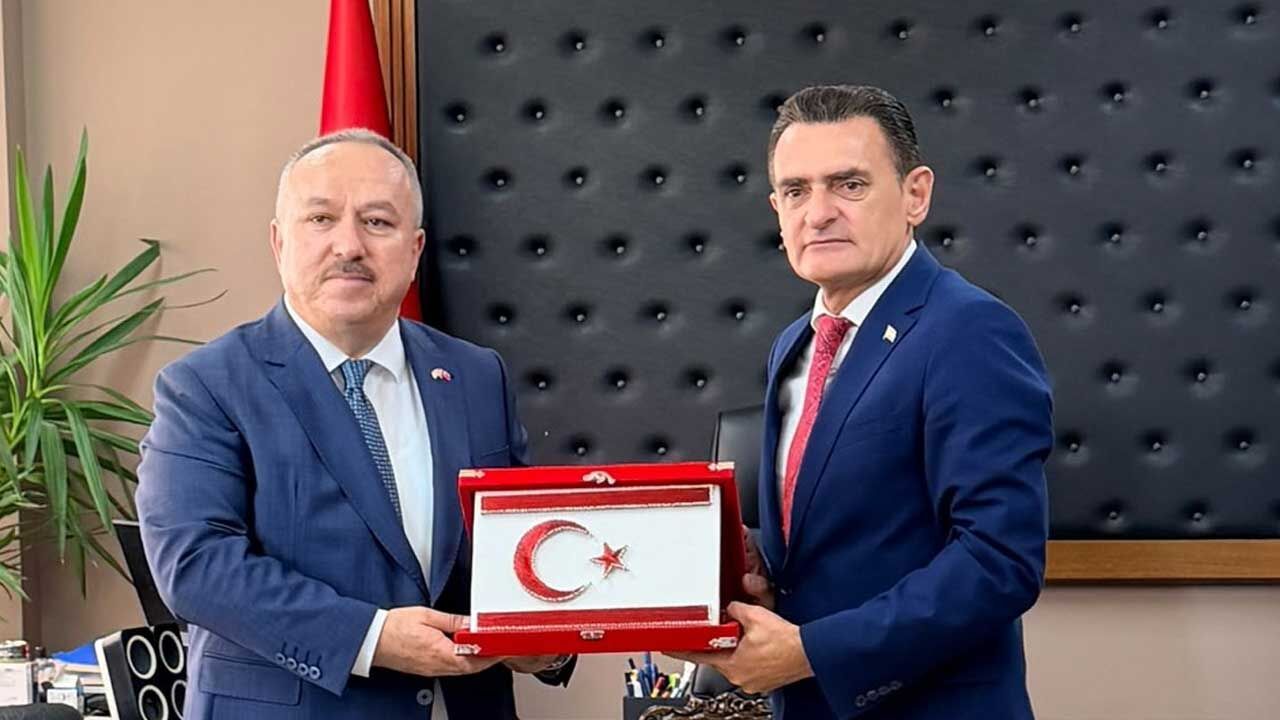 Oğuz konuşma yaparken mikrofonların önünde ciddiyetle duruyor.