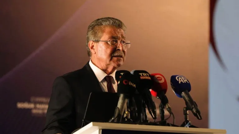 Üstel konuşurken arka planda Güzelyurt manzarası ve tarım öğeleri görülüyor