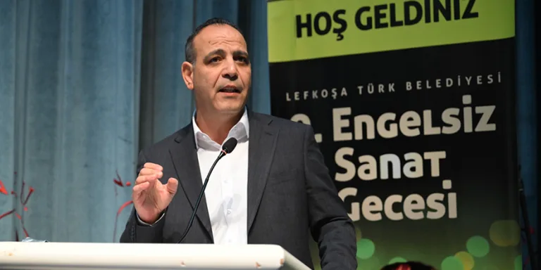 Harmancı konuşurken mikrofon önünde duruyor; Lefkoşa Yarı Maratonu gelirinin ailelere aktarılmasını öneriyor