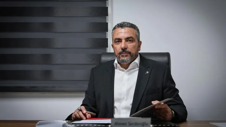 Serdaroğlu konuşma yaparken mikrofon önünde, arka planda toplantı ortamı