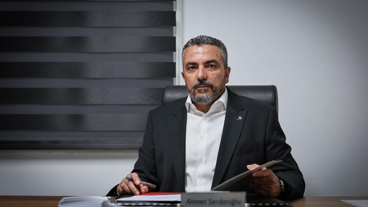 Serdaroğlu konuşma yaparken mikrofon önünde, arka planda toplantı ortamı