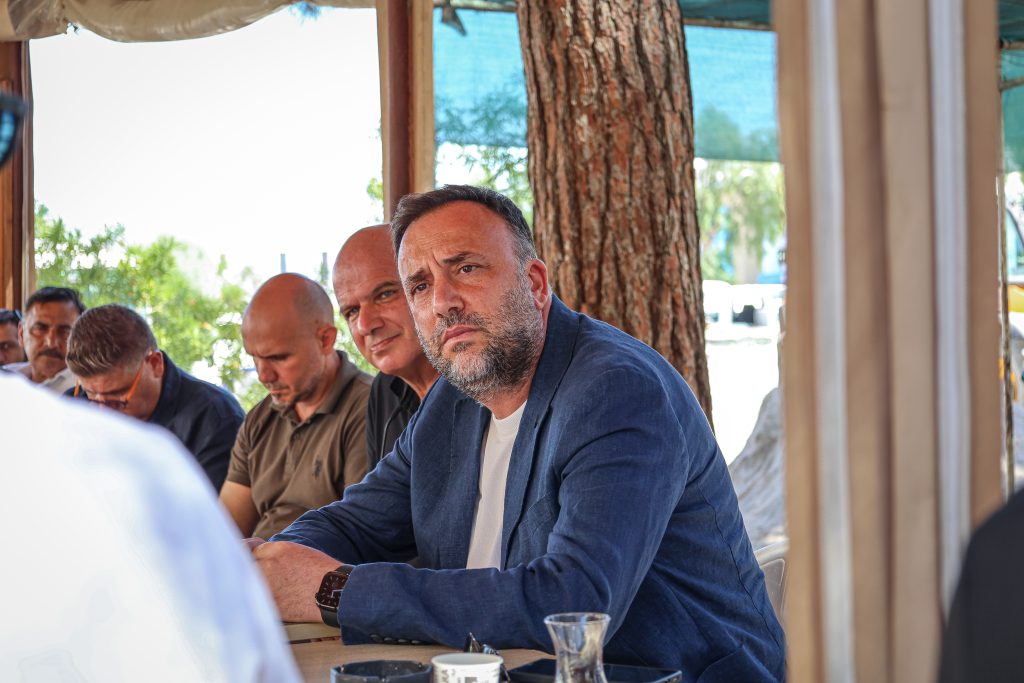Çeler konuşurken mikrofon önünde duruyor, vurgu yapar şekilde el hareketi yapıyor