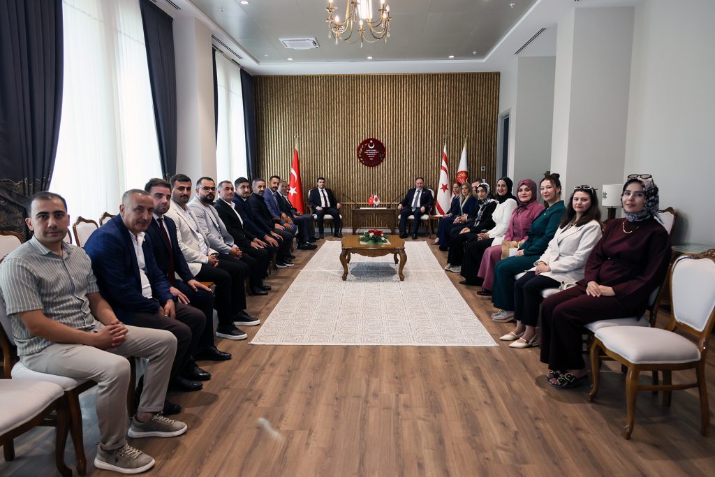 Öztürkler konuşuyor; arkada Kıbrıs Türk bayrağı ve dinleyici kalabalığı görünüyor
