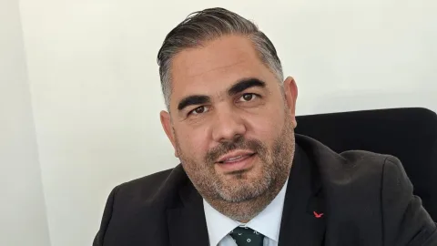 Rahvancıoğlu konuşurken mikrofonlu bir sahnede, belediye yatırımlarını vurguluyor