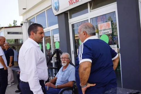 Belediye yetkilisi mikrofonla konuşurken, arka planda parti veya kurum logosu görünür