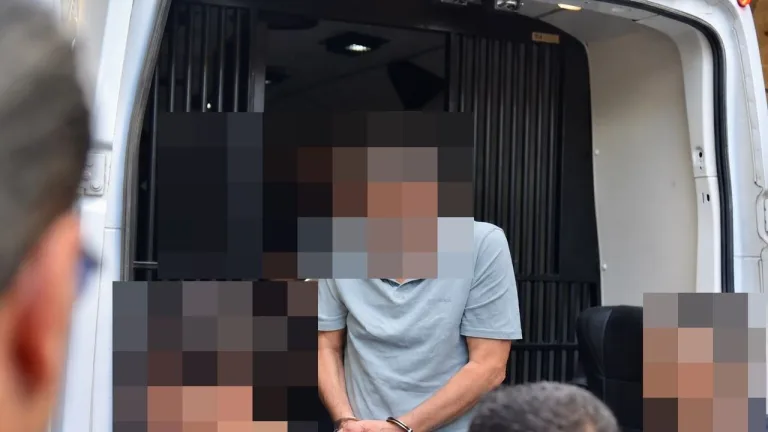 Gemi faciası zanlılarının adliyeye getirilişi veya duruşma görüntüsü — siyah arka plan veya belirsiz figürler