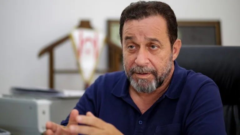 Denktaş konuşma yaparken mikrofonlar ve arka planda parti bayrakları