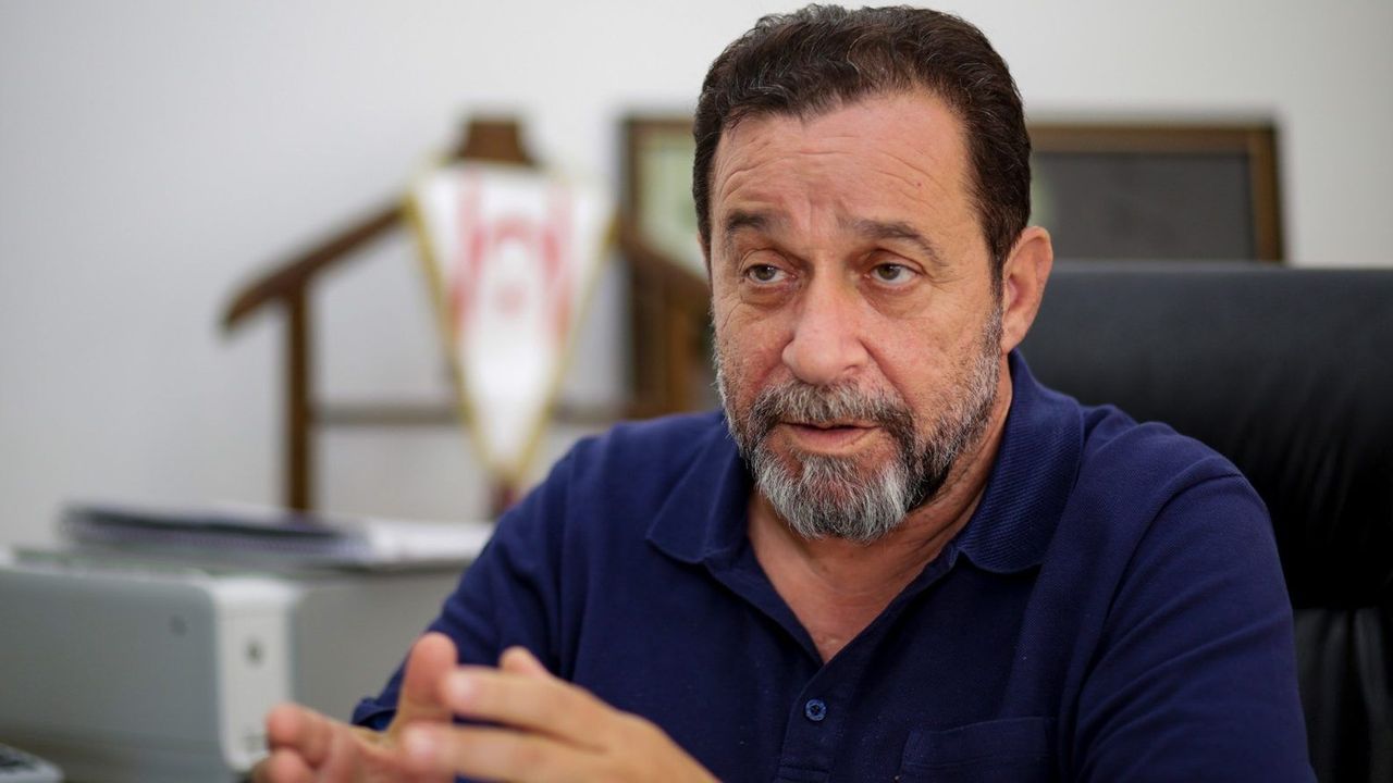Denktaş konuşma yaparken mikrofonlar ve arka planda parti bayrakları