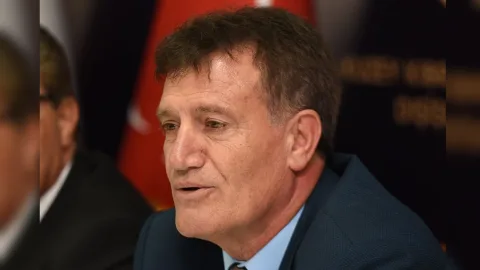 Erhan Arıklı konuşurken mikrofon ve yorum alanı önünde duruyor