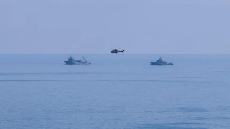 Üstel konuşurken, arka planda deniz ve kurtarma çalışmaları için bekleyen ekipler ve ekipmanlar