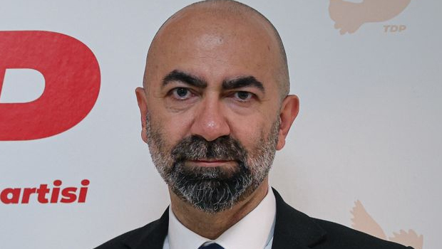 Kemal Baykallı konuşurken mikrofon önünde, arka planda TDP logosu ve parti renkleri