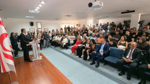 Üstel konuşurken gençlerle birlikte salondaki topluluğa bakıyor