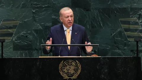 Cumhurbaşkanı Erdoğan konuşma yaparken kürsü önünde mikrofonlar ve Türk bayrağıyla görüntüleniyor
