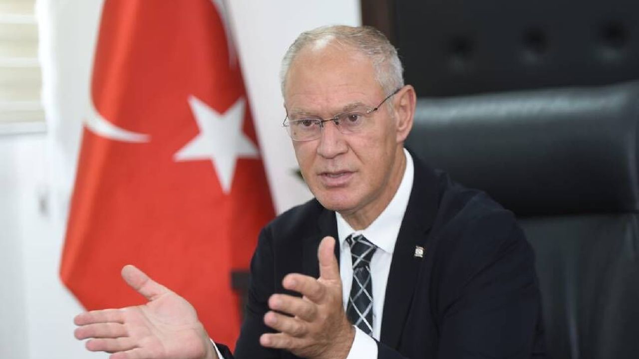 Hasipoğlu konuşma yaparken notlara bakıyor, arka planda Türkiye bayrağı ve yasa taslağı görünüyor