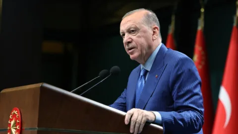 Cumhurbaşkanı Erdoğan konuşma yaparken mikrofon önünde, vurgulu ifadelerle dinleyenlere sesleniyor
