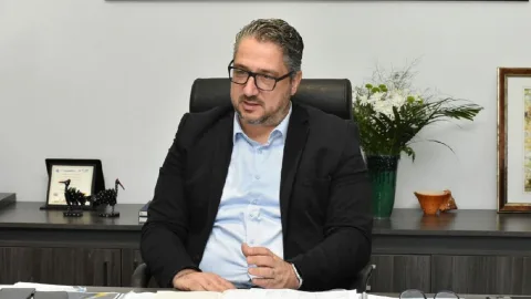 Şenkul konuşurken ciddi ifadeyle el hareketi yapıyor.