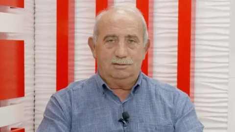 Topaloğlu konuşurken mikrofon önünde, arka planda toplantı veya basın ortamı bulanık görünüyor