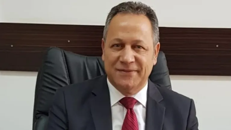 Enver Öztürk konuşurken mikrofon önünde ceket giymiş görüntü