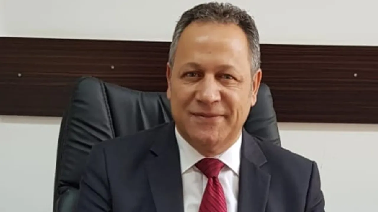 Enver Öztürk konuşurken mikrofon önünde ceket giymiş görüntü