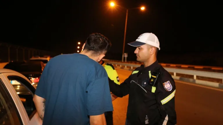 Polis ekipleri durdurulan araçlarla inceleme yapıyor, bazı sürücüler prosedürlere uymak üzere bekliyor