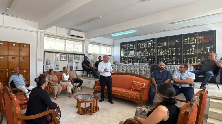 Kansoy mikrofonla konuşurken arka planda Güzelyurt yazılı pankart ve katılımcılar
