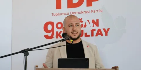 Ekinci konuşurken mikrofon önünde, ekonomi vurgusuyla ciddi ifade