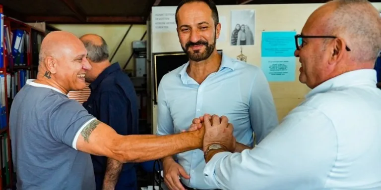 Kansoy konuşuyor; arka planda Güzelyurt yazılı pankart ve dinleyiciler