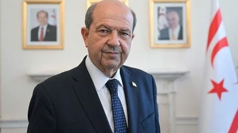 Tatar konuşma yaparken mikrofon ve Türk bayrağı önünde duruyor