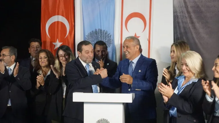 Denktaş konuşurken mikrofon önünde, ifadeleri kararlı ve yüzü net şekilde görünür.