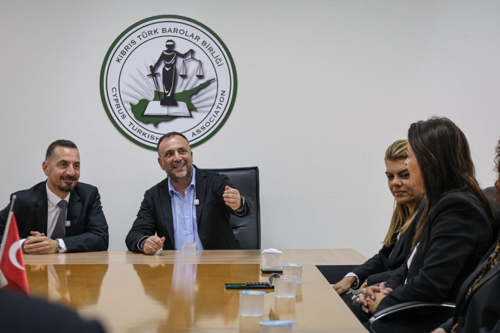 Çeler konuşurken mikrofonlar ve dizi halinde sandalyeler arka planda