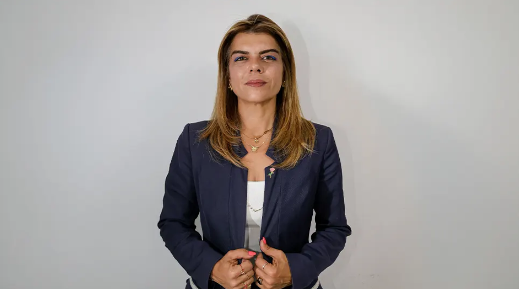 Ayşe Öztabay konuşma yaparken mikrofonlara bakıyor; arka planda siyasi pankartlar ve izleyiciler var