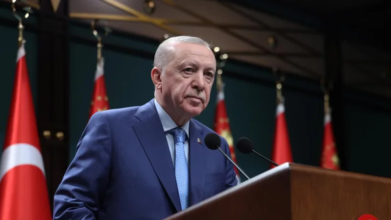 Cumhurbaşkanı Erdoğan konuşma yaparken mikrofonların önünde oturuyor