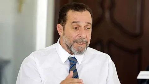Denktaş konuşma yaparken el hareketiyle bir konferans salonunda duruyor