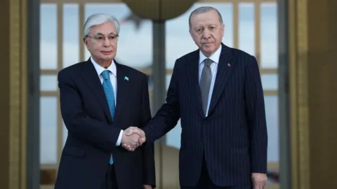 Cumhurbaşkanı Erdoğan ve Kazakistan Cumhurbaşkanı Tokayev el sıkışırken karşılıklı sohbet ediyor