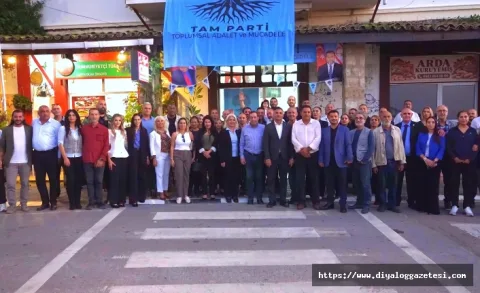 Etkinlikte sahnede konuşan ve salonu dolduran katılımcılar