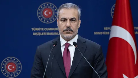 Fidan konuşurken ciddiyetle dinleyen kişilerle birlikte kürsü veya toplantı ortamı