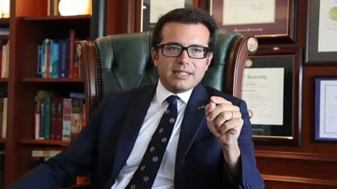 Murat Metin konuşurken mikrofon önünde, haber röportajı ortamı