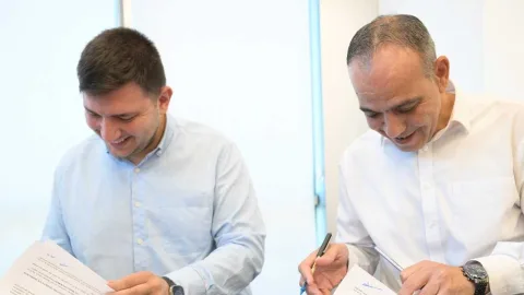 LTB yetkilileri ve Kıbrıs Türk Gençlik Federasyonu temsilcileri birlikte protokol imzalarken masa önünde duran belgeler