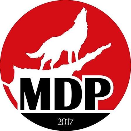 MDP logosu veya parti yetkilileri konuşma yaparken mikrofon ve arka planda parti pankartı