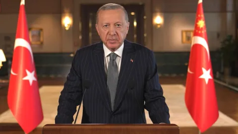 Cumhurbaşkanı Erdoğan konuşma yaparken Türk bayrağı arka planda görünüyor